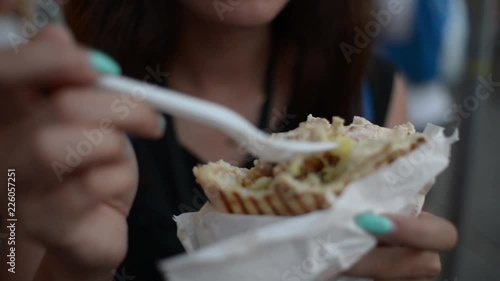 Young woman tourist eating Doner Kebab at the night street Krakow - close up