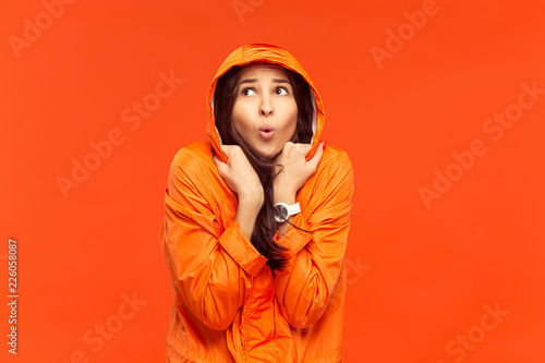 The young girl posing at studio in autumn jacket isolated on red. Human negative emotions. Concept of the cold weather. Female fashion concepts © master1305