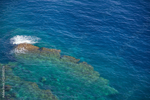 Felsen an Küste aus Vogelperspektive mit tiefem blauem Meer