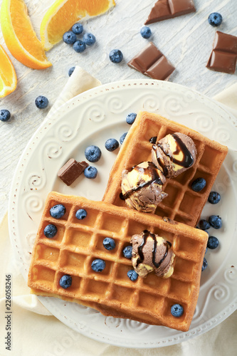 Delicious waffles with ice cream and blueberries on plate