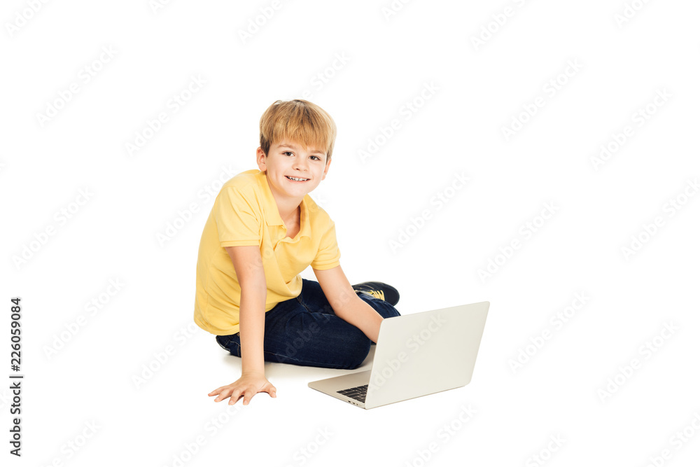 happy little boy using laptop and smiling at camera isolated on white happy little boy using laptop and smiling at camera isolated on white