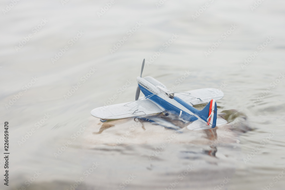 Scale model hydroairplane on the surface of water. The plane begins to drown after an unsuccessful landing. Copy space. Toy Scale model hydroairplane on the surface of water. The plane begins to drown after an unsuccessful landing. Copy space. Toy