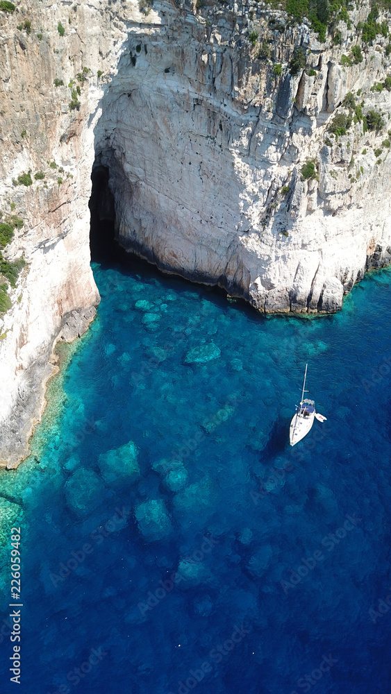 Aerial drone bird's eye view photo of tropical rocky bay of Ortholithos with famous cave of Papanikolis and turquoise calm waters forming a blue lagoon