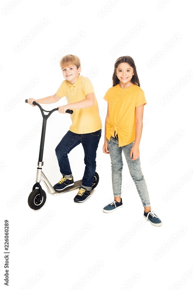 high angle view of happy children standing with scooter and smiling at camera isolated on white high angle view of happy children standing with scooter and smiling at camera isolated on white