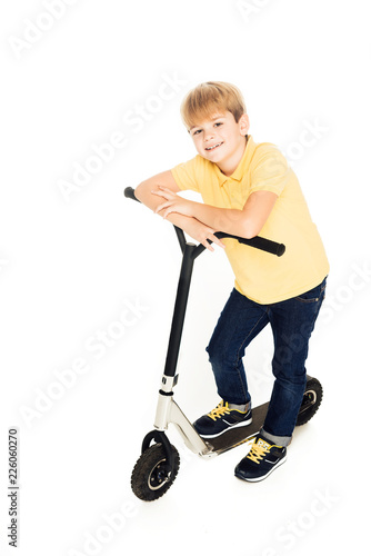 cute happy little boy leaning at scooter and smiling at camera isolated on white