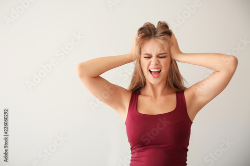 Stressed young woman on light background