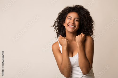 Happy black girl celebrating her success on light background