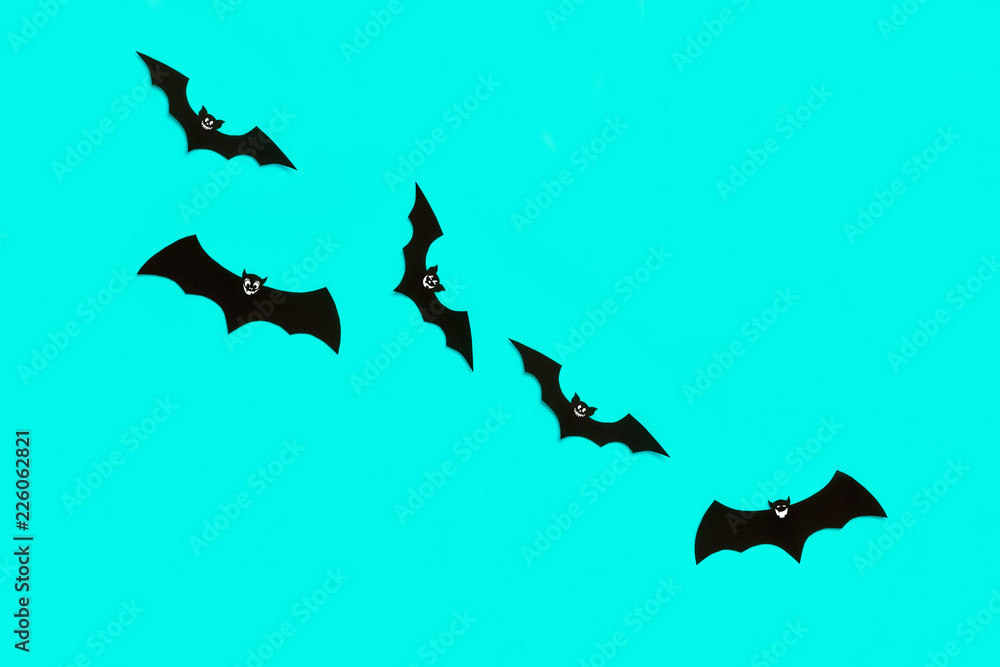 Obraz premium Halloween and decoration concept. Cute smiling black paper bats flying over pastel blue background. Halloween background.