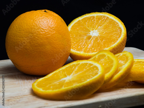 Naranja y media sobre tabla de madera y fondo negro