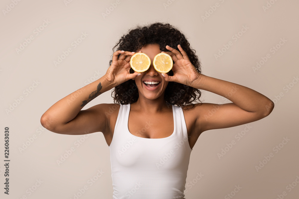 African-american woman with lemon halves near eyes