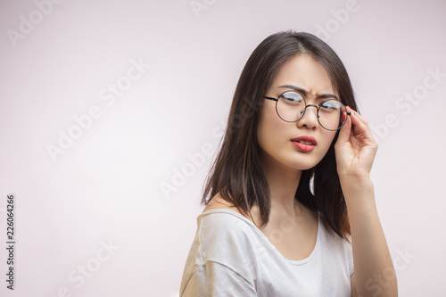 Discontent Asian young woman feels eyestrain ajusting optical computer glasses, eyesight problem correction, fatigue, overwork and stress at work concept photo