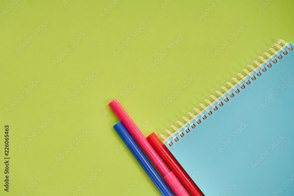 notebook with colorful pens on green background notebook with colorful pens on green background