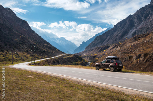 Crossover car on the asphalt road in the mountains at sunny weather