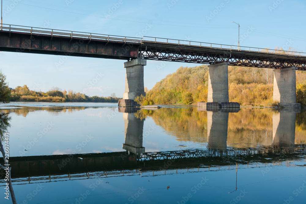 Fototapeta premium Old bridge over the river. Autumn landscape with a bridge