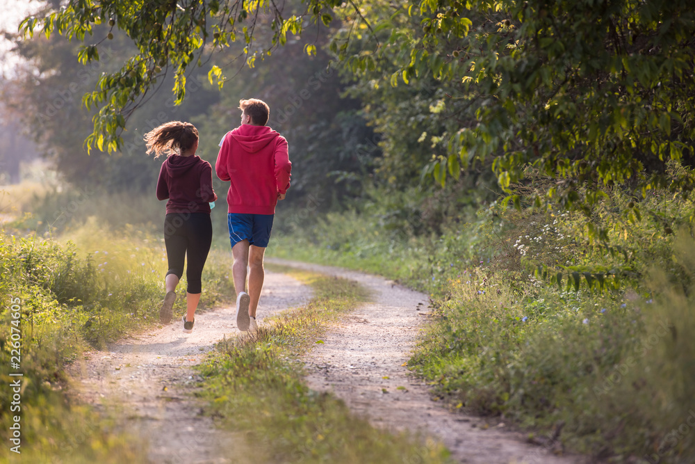 Obraz premium young couple jogging along a country road