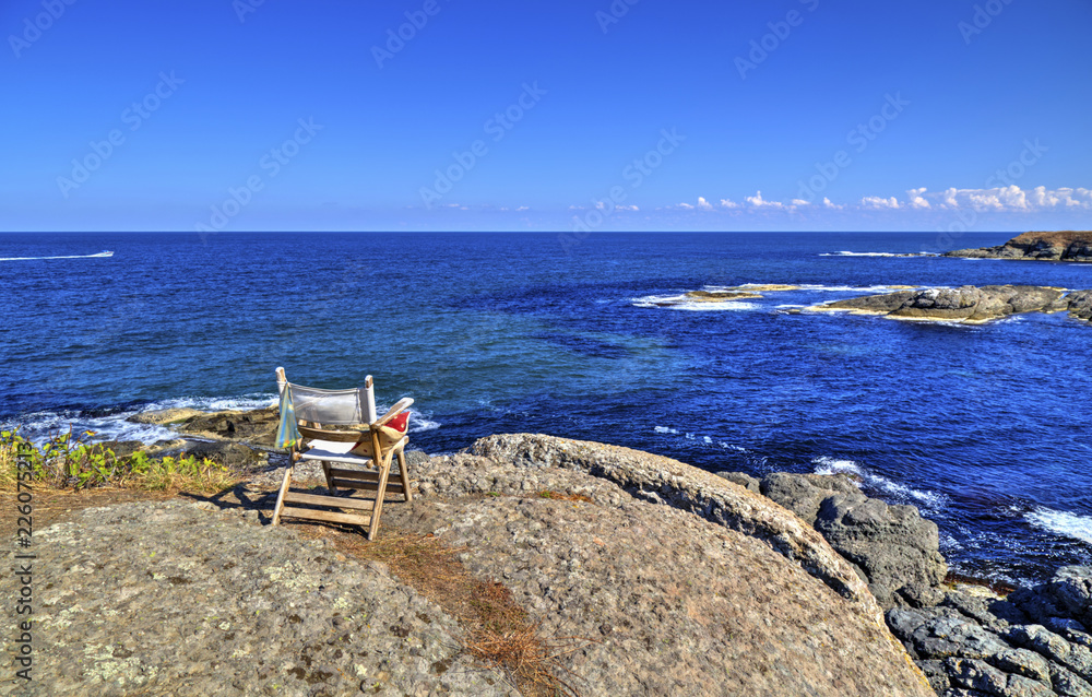 Beautiful landscape with wooden chair on rocky shore