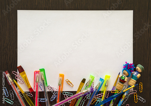 Empty white sheet of paper for your text. There are colored pencils, pens, paper clips around it.