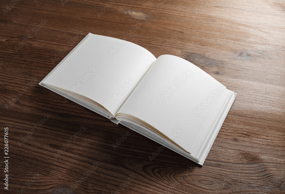 Blank open book or notebook on wood table background. Responsive design mockup. Blank open book or notebook on wood table background. Responsive design mockup.