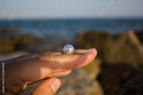 pearl in a hand against the background of the sea