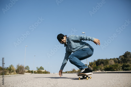 Trendy man in denim and cap skateboarding