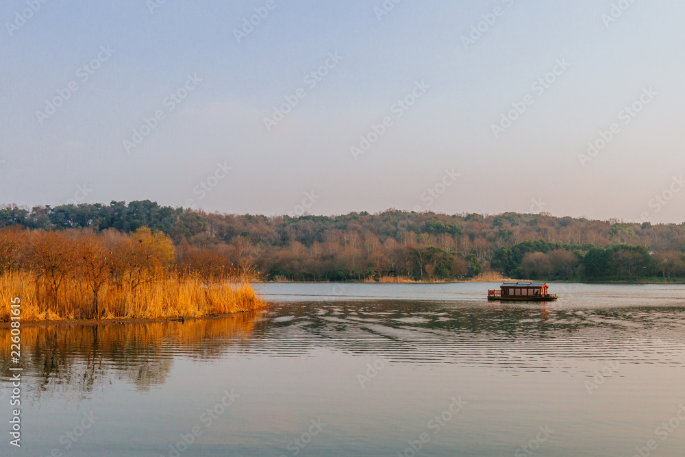 Boat traveling on West Lake at dusk in Hangzhou