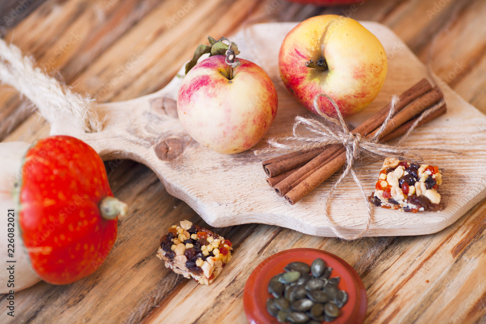  Set of pumpkins, apples and nuts with maple leaves on the wooden background. Autumn mood. Thanksgiving concept. Healthy food, diet, lifestyle and holiday theme. Top view. Close up.