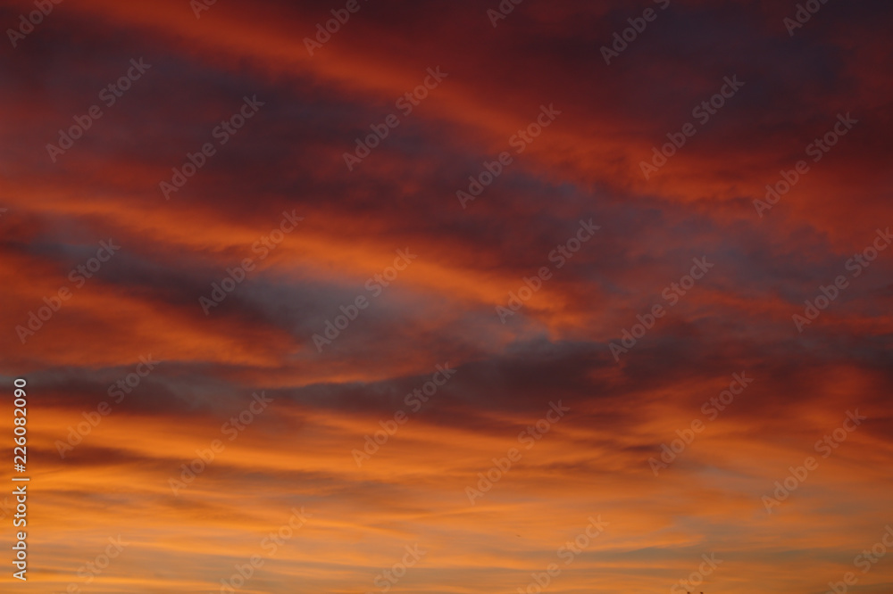 Beautiful Vibrant Pink Red and Orange Diagonal Sunset Cloud Pattern With Blue Sky Showing In Between