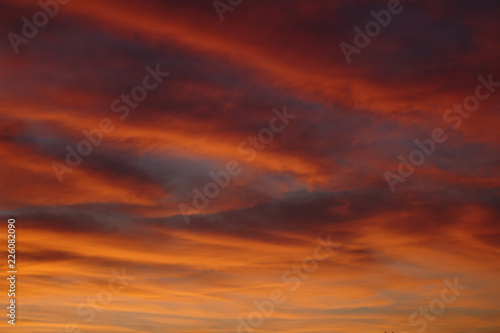 Beautiful Vibrant Pink Red and Orange Diagonal Sunset Cloud Pattern With Blue Sky Showing In Between © Kelsey