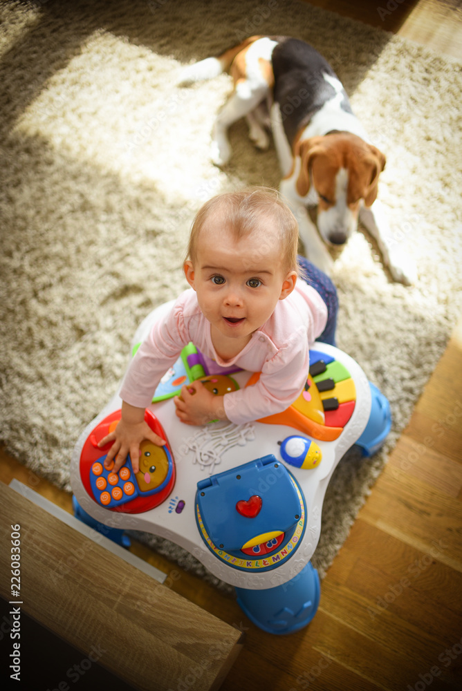 Fototapeta premium Baby girl stands next to cafe table in living room