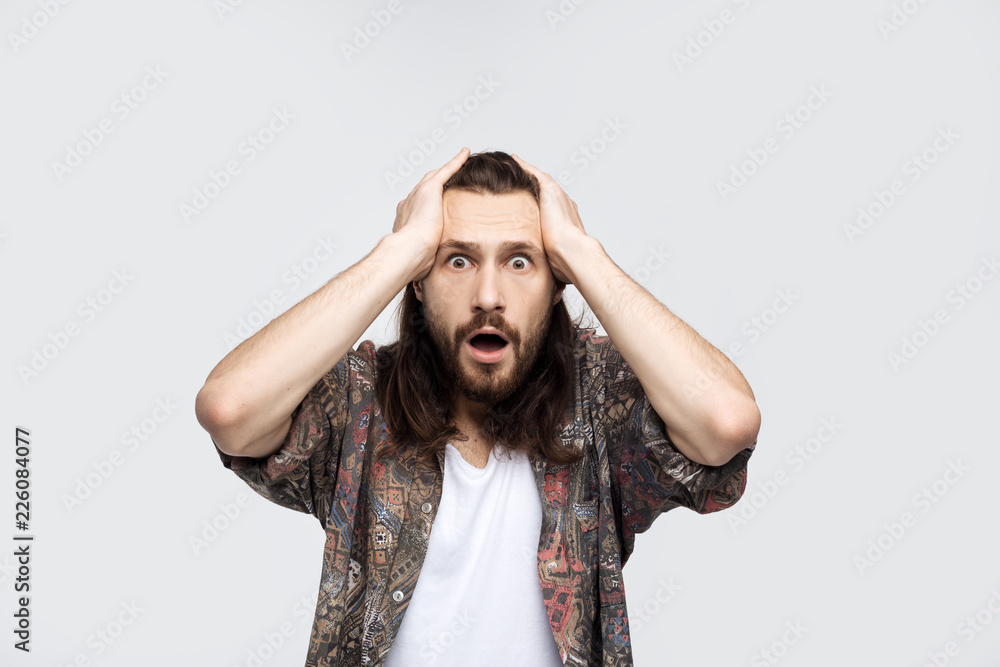 Indoor shot of puzzled and confused man with bristle scratching head and opening mouth while looking at camera and standing over white background. Problems at work and an error while performing Indoor shot of puzzled and confused man with bristle scratching head and opening mouth while looking at camera and standing over white background. Problems at work and an error while performing