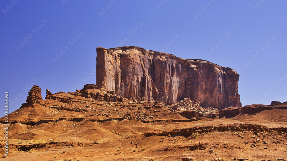 Fototapeta premium Big wall of rock on a desert on a blue sky as background