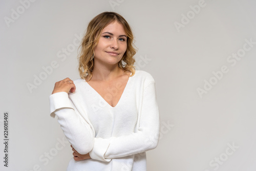 Portrait of a beautiful blonde girl on a white background in a dress.