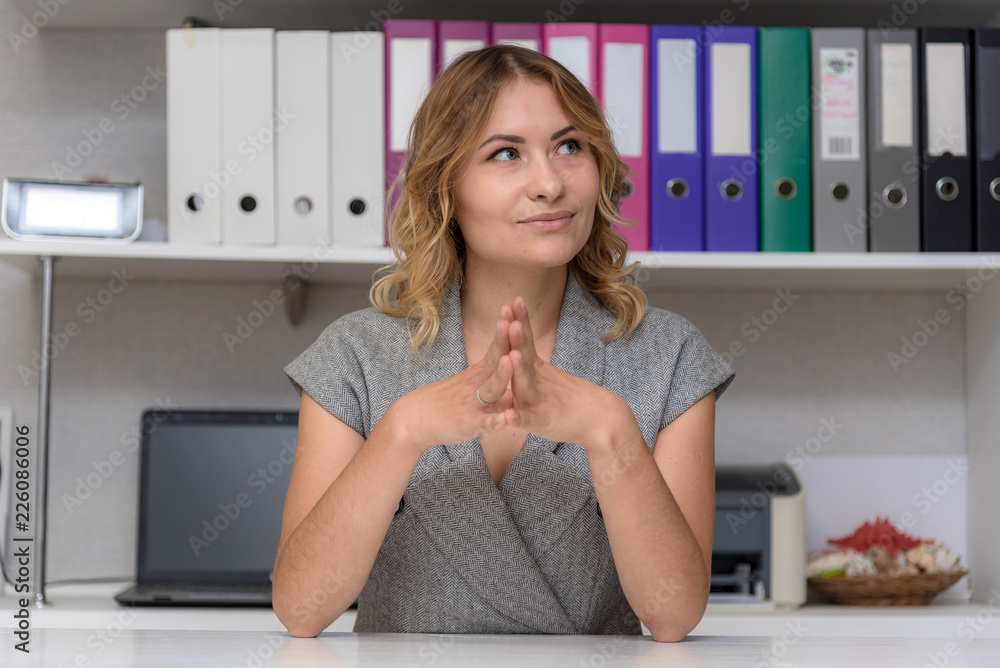 Portrait of a beautiful blonde girl in the office at the table. Portrait of a beautiful blonde girl in the office at the table.