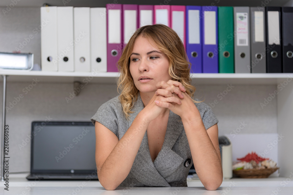 Portrait of a beautiful blonde girl in the office at the table. Portrait of a beautiful blonde girl in the office at the table.
