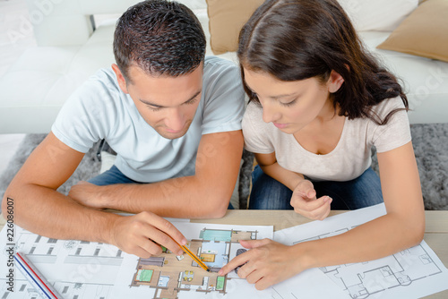 young couple looking at blueprint project together