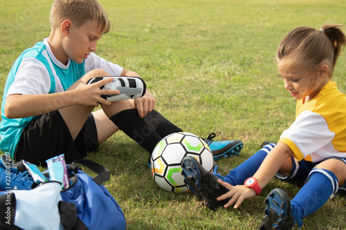 Soccer players adjusting shoes and socks on field before playing. 