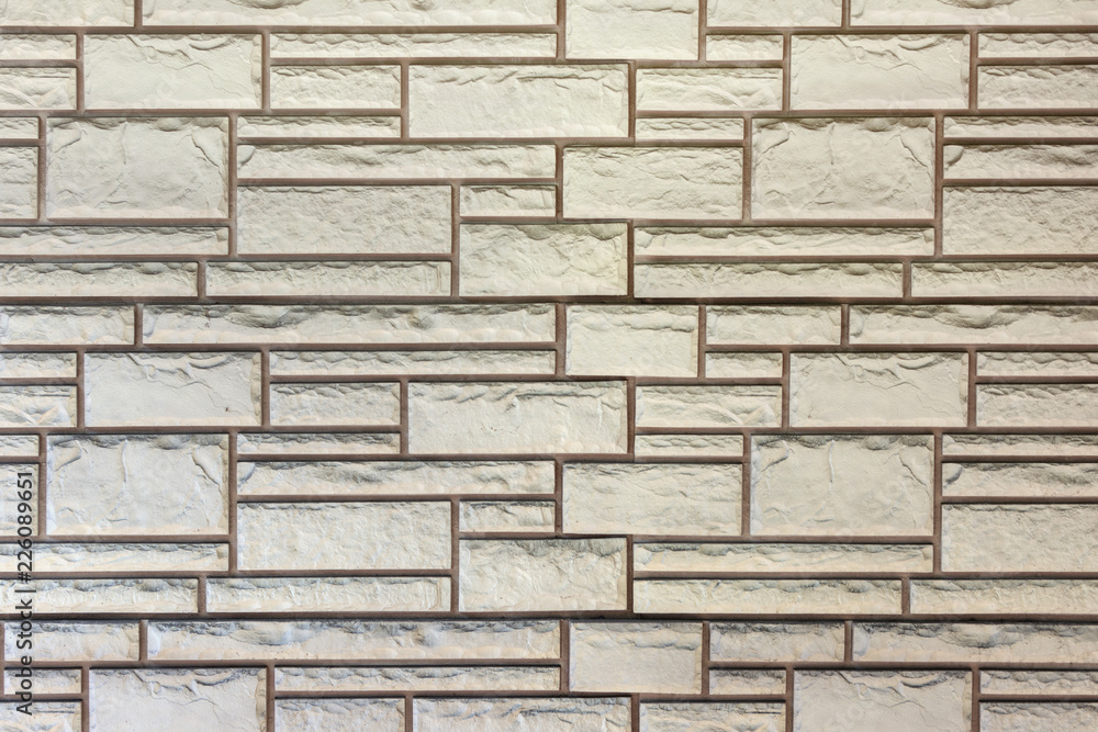 Naklejka premium Wall of light beige bricks of different sizes. Background with texture brickwork.