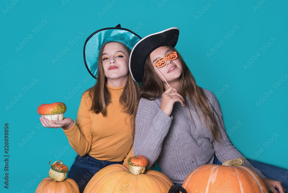 Portrait of two happy young women in black witch halloween costumes on