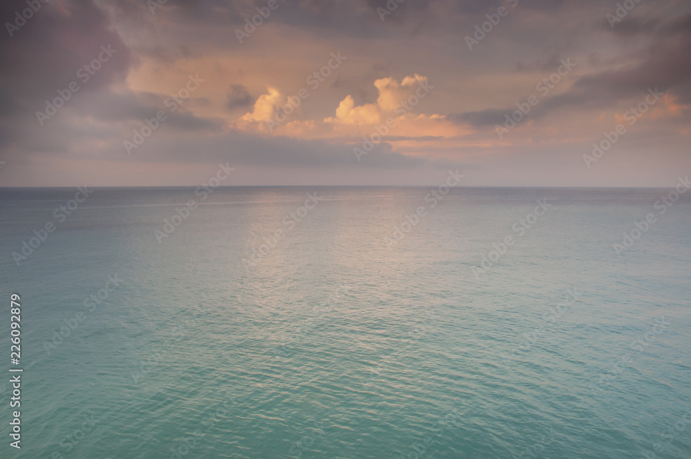 Delicate sunset over the azure sea with beautiful pastel colors. A minimalistic view of the tropical sea with the sky.