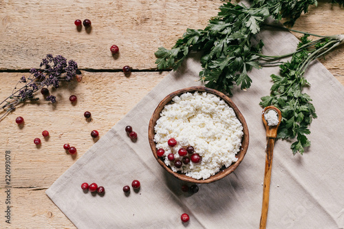 Fototapeta Naklejka Na Ścianę i Meble -  flat lay. fresh herbs, farmer cottage cheese in a ceramic bowl with a spoon and berries on a wooden background