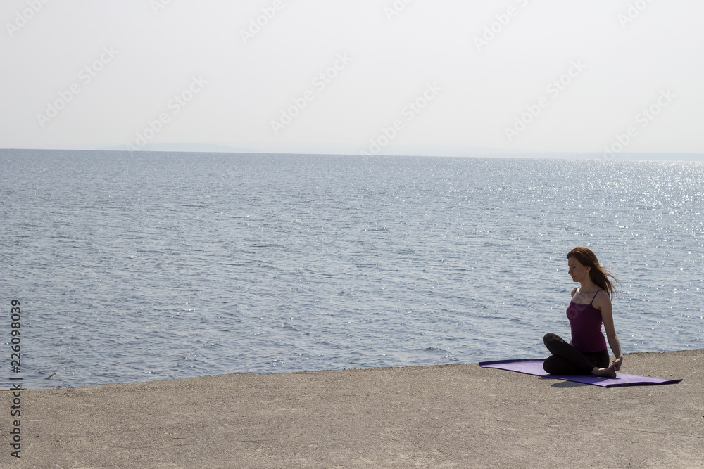 Young attractive woman doing yoga outdoors. Landscape of the river bank and young woman in yoga pose practising