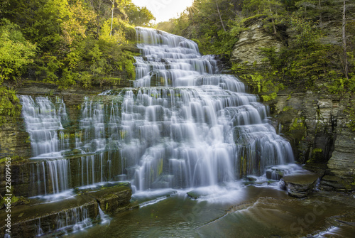 Beautiful sunrise over Hector Falls at Watkins Glen  upstate New York  featuring sun beaming trough the trees on the background