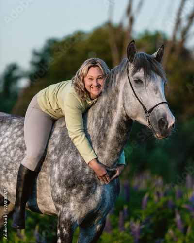 Happy smiling woman embracing a horse. Rider on a horseback.