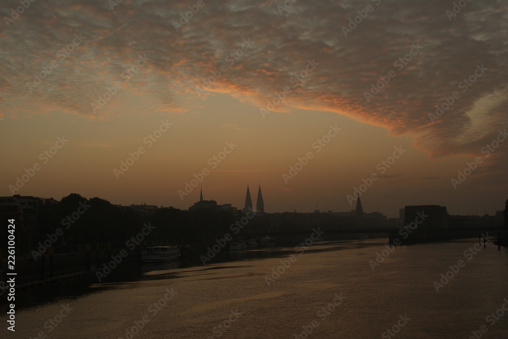 Sunrise in Bremen city in summer with trees on river weser and beautifyl sky clouds