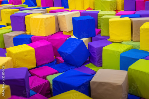 A young man or boy, father playing and jumping in soft cubes in the dry pool of the game children's room for birthday. entertainment centre. indoor playground in foam rubber pit in trampoline.