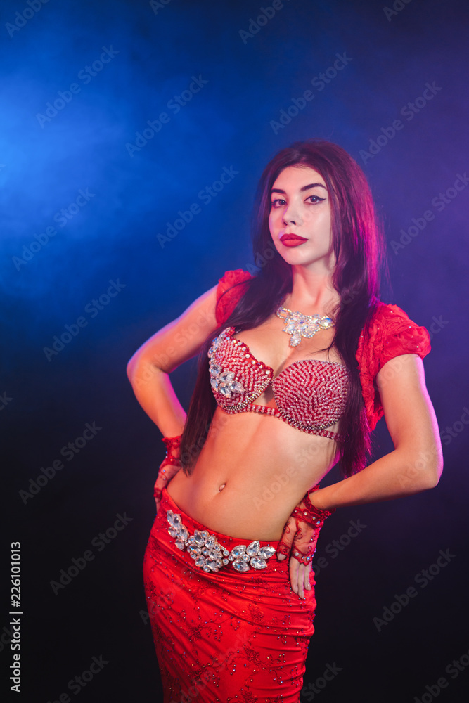 Woman in exotic costume sexually moves semi-nude body. Sexy traditional  oriental belly dancer girl dancing on blue neon wall. Muslims, temptation  concept. Spectacular show Stock Photo | Adobe Stock