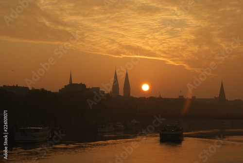 Sunrise in Bremen City view on Weser river with a transport vessel boat going on weser