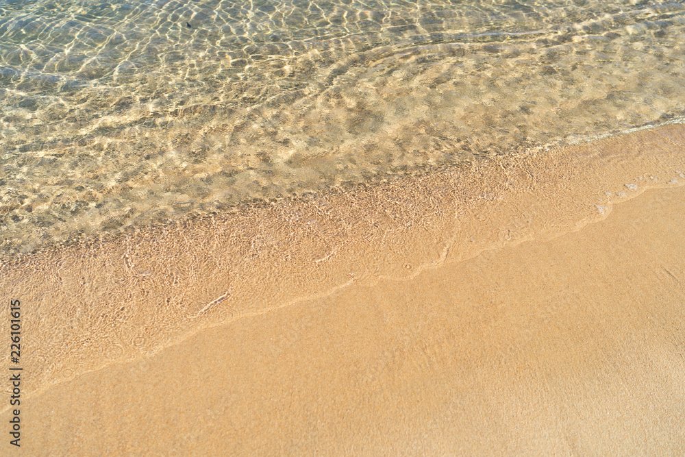 Beachline with bright orange-yellow sand and still transparent sea water in natural light at noon Beachline with bright orange-yellow sand and still transparent sea water in natural light at noon