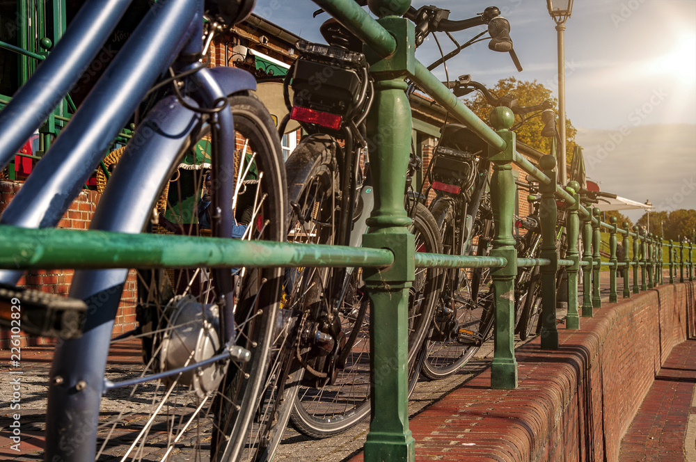 Fahrräder an einem Metallzaun in einem Hafen bei Sonnenlicht und blauem Himmel