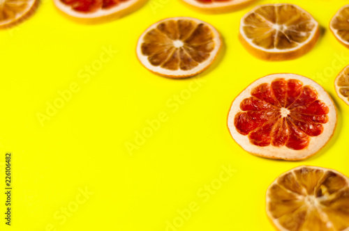 Scattered dried slices grapefruit and lemon on yellow background with copy space